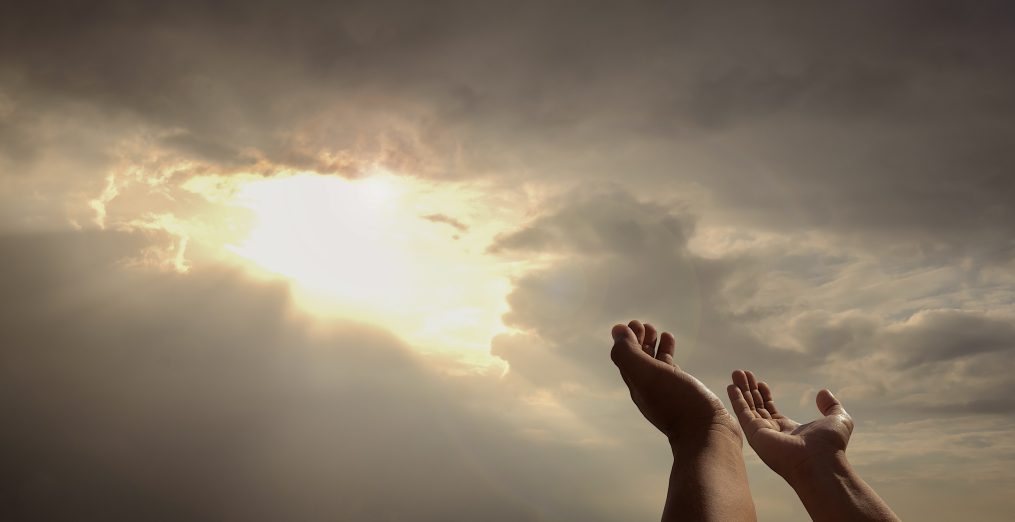 praying hands of a man for blessings his god on the sunset